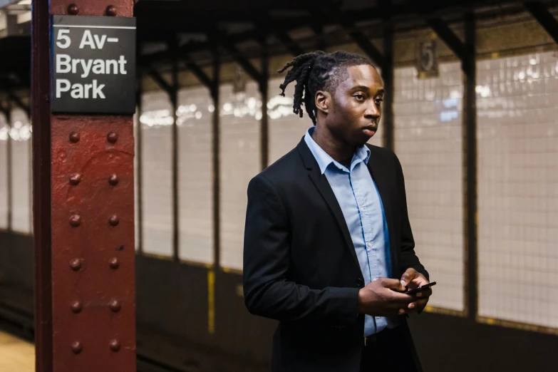 a man standing in a train station holding a cell phone, pexels contest winner, renaissance, playboi carti portrait, in new york, black main color, lawyer