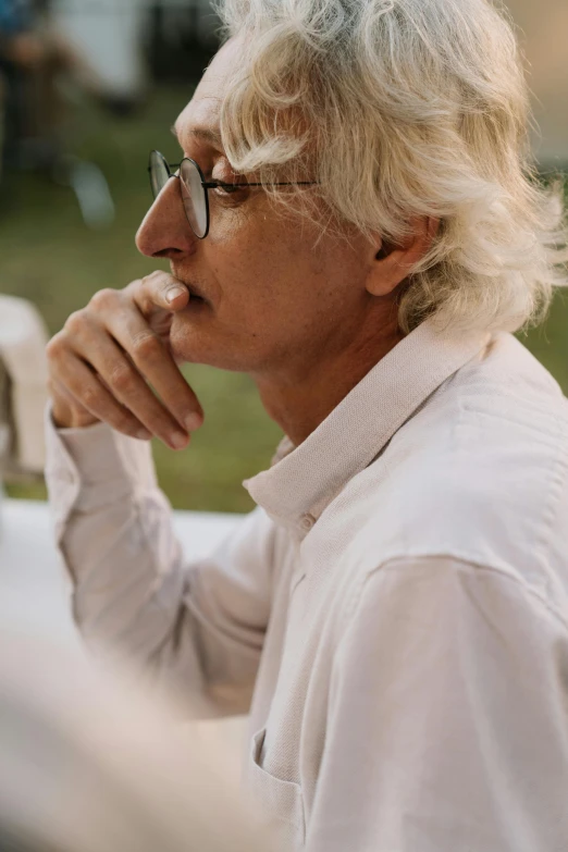 a close up of a person sitting at a table, by Jan Tengnagel, white hair color, fine white shirt, al fresco, pondering