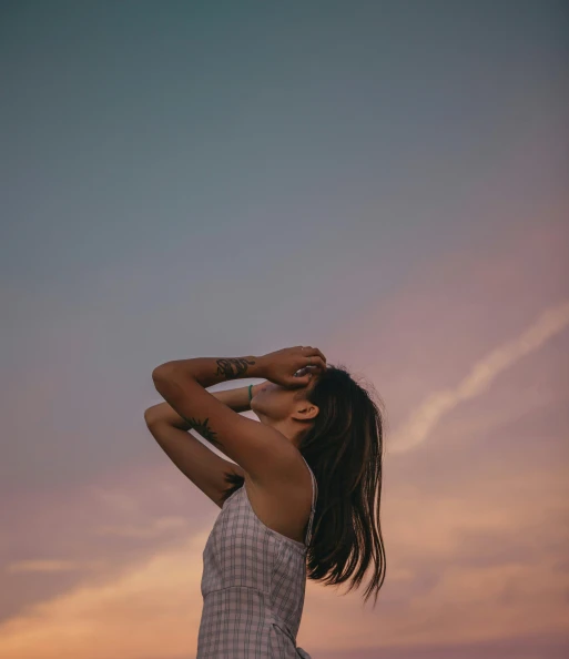a woman standing on top of a beach next to the ocean, by Carey Morris, pexels contest winner, aestheticism, looking up into the sky, sunset glow around head, with closed eyes, faded colors