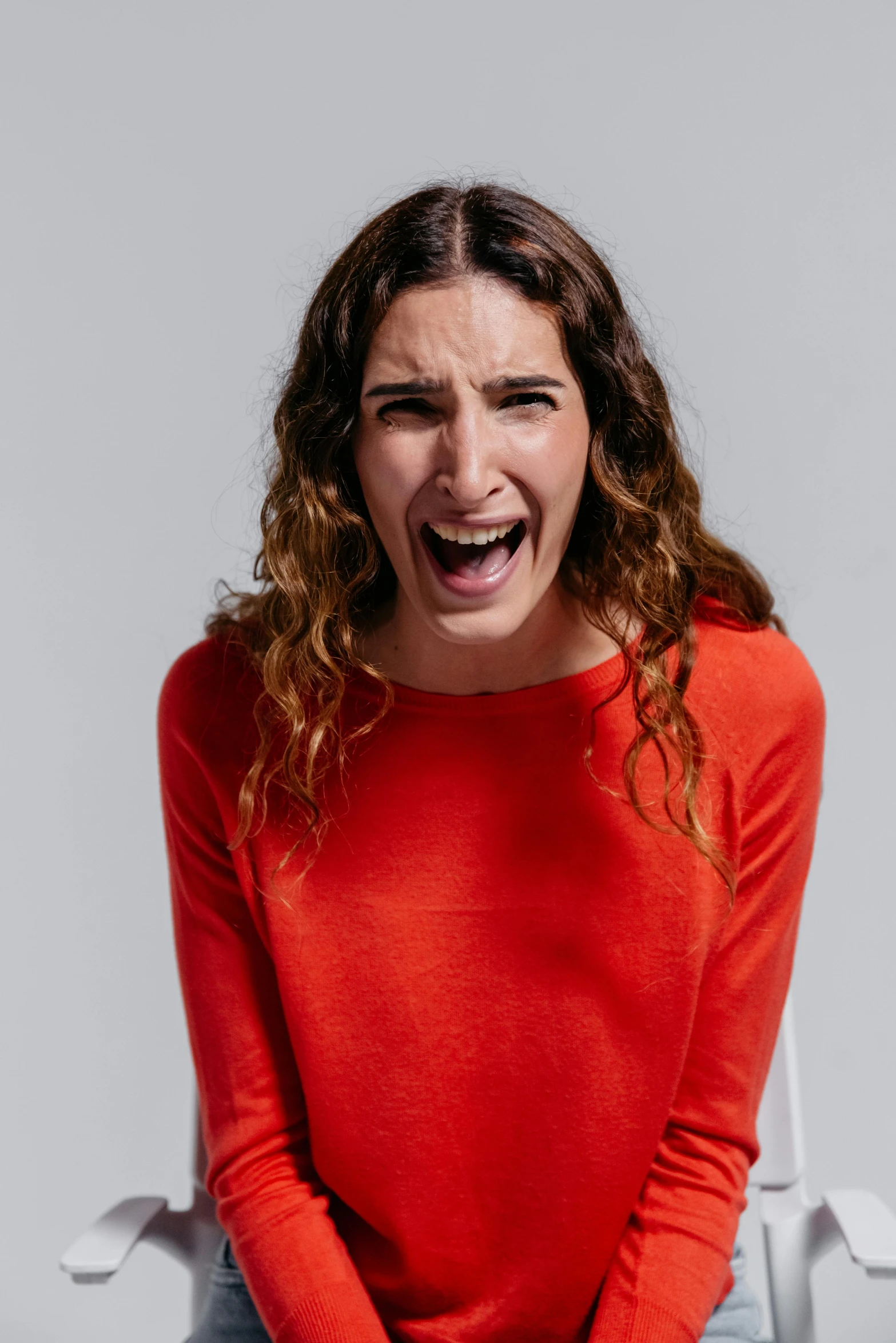 a woman sitting on a chair with her mouth open, shutterstock contest winner, antipodeans, ross geller screaming, red clothes, young angry woman, studio shot