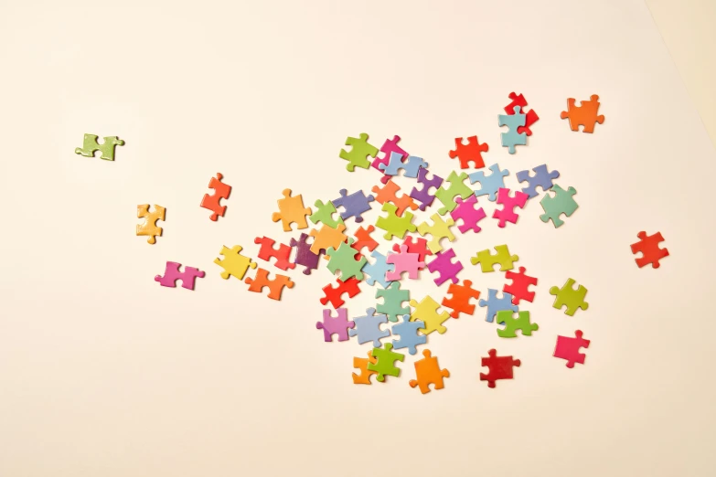 a pile of puzzle pieces sitting on top of a table, a jigsaw puzzle, by Carey Morris, trending on pexels, plain background, sterile colours, floating particles, pastel artwork