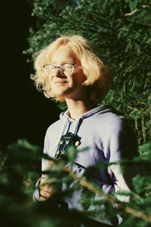 a woman with glasses standing in front of a tree, an album cover, featured on reddit, pale hair, young man in a purple hoodie, nina tryggvadottir, full frame image