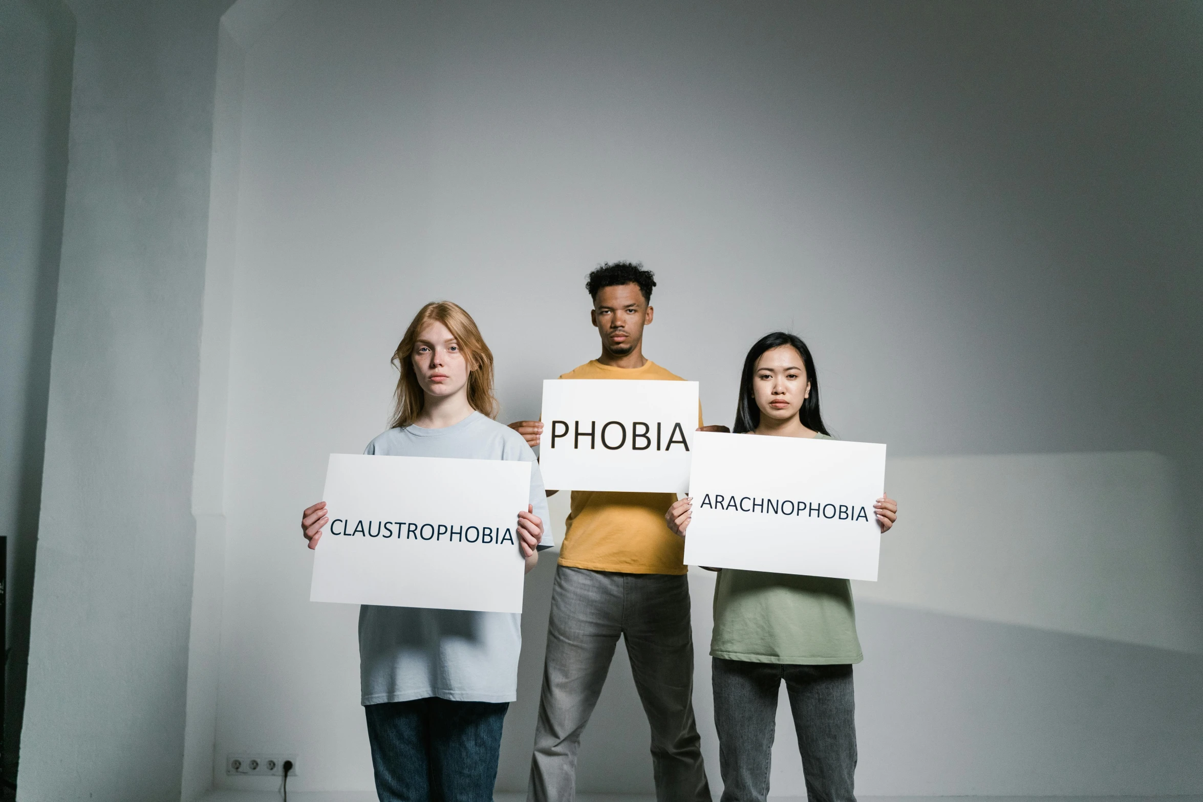 a group of people holding up signs in a room, trending on pexels, antipodeans, phobia, in front of white back drop, achluophobia, athmospheric