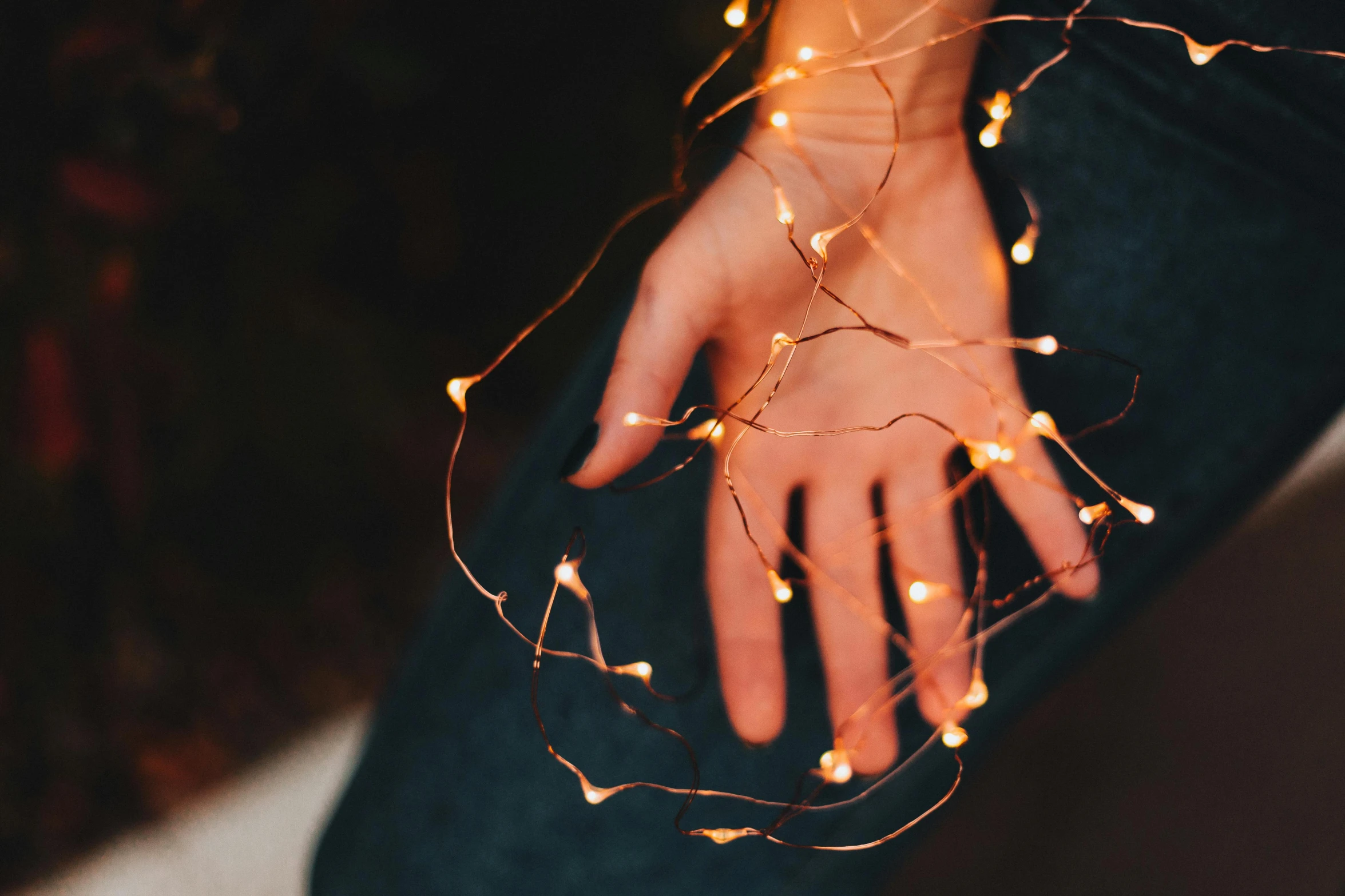 a close up of a person's hand holding a string of lights, inspired by Elsa Bleda, trending on pexels, orange glowing hair, instagram post, light scatter, wearing light