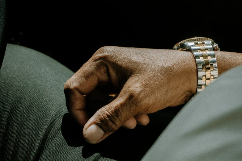 a close up of a person holding a watch, by Dan Frazier, trending on pexels, visual art, black man, seated in royal ease, pointing index finger, thumbnail