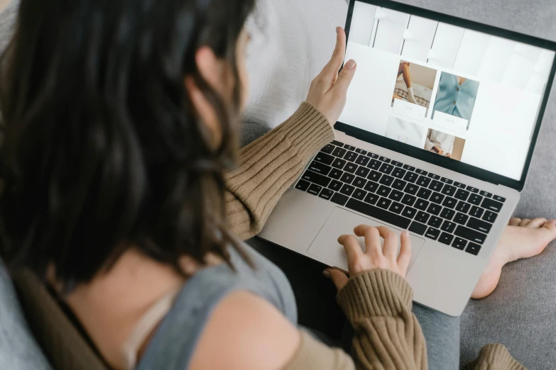 a woman sitting on a couch using a laptop computer, a picture, trending on pexels, flatlay, close up to the screen, woman with braided brown hair, sitting on a bed