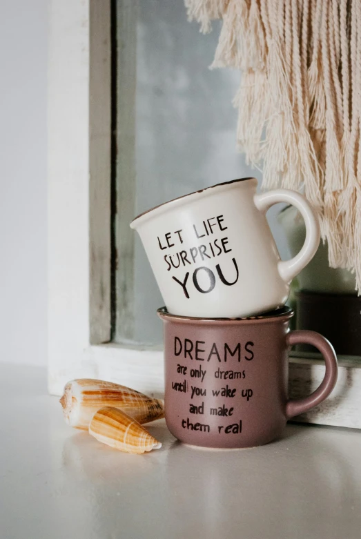 a couple of cups sitting on top of a window sill, a picture, by Dulah Marie Evans, unsplash, you may say i'm a dreamer, vintage muted colors, in white lettering, cottagecore hippie