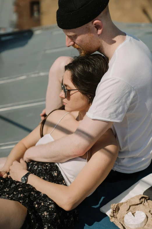 a man and a woman sitting next to each other, pexels contest winner, happening, cuddling, on ship, shaded, sydney hanson