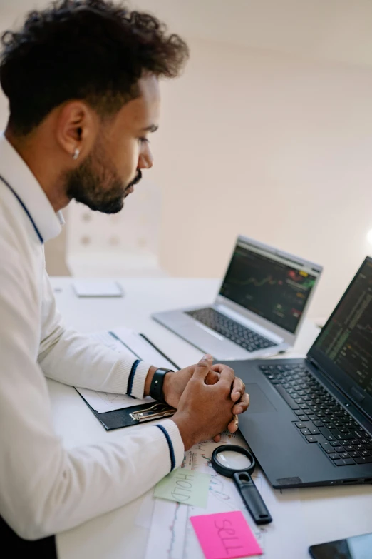 a man sitting at a desk working on a laptop, a computer rendering, by Adam Rex, pexels, wearing a white lab coat, dark-skinned, trading stocks, sad man