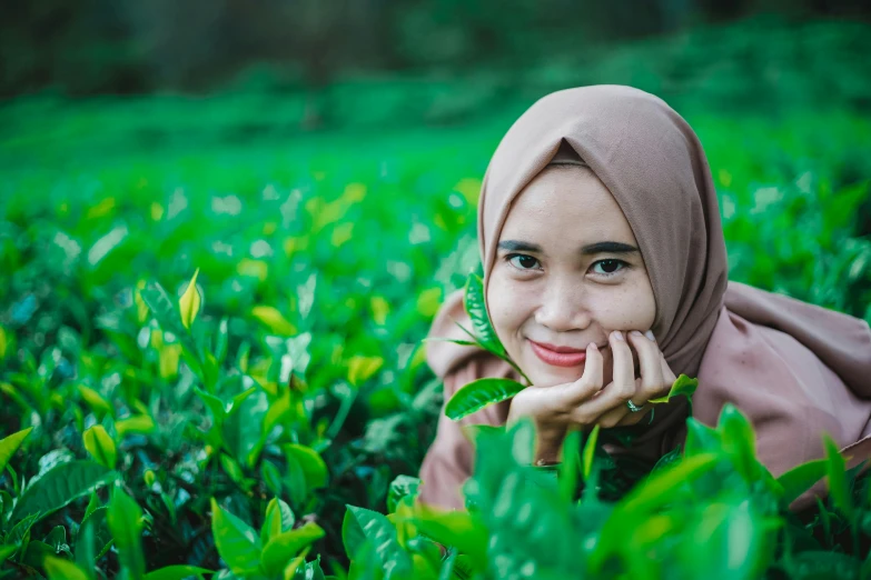 a woman laying on top of a lush green field, a picture, by Basuki Abdullah, shutterstock, hurufiyya, avatar image, close up portrait photo, green tea, square