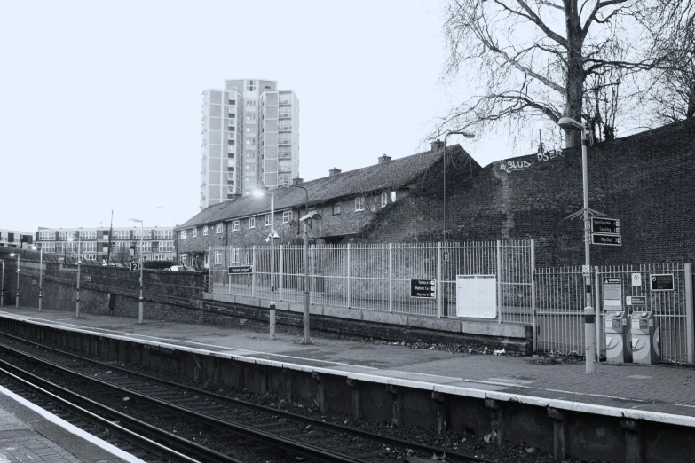 a black and white photo of a train station, a black and white photo, inspired by Thomas Struth, brutalism, barnet, urban in background, thumbnail, yard