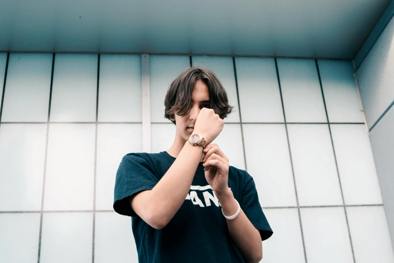 a young man standing in front of a building, by Nina Hamnett, trending on unsplash, rapper jewelry, frank dillane, wearing a watch, thinking pose