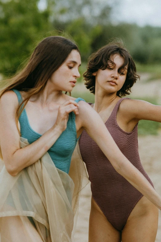 two women standing next to each other on a beach, unsplash, renaissance, wearing leotard, muted colored bodysuit, supple look, zoomed in