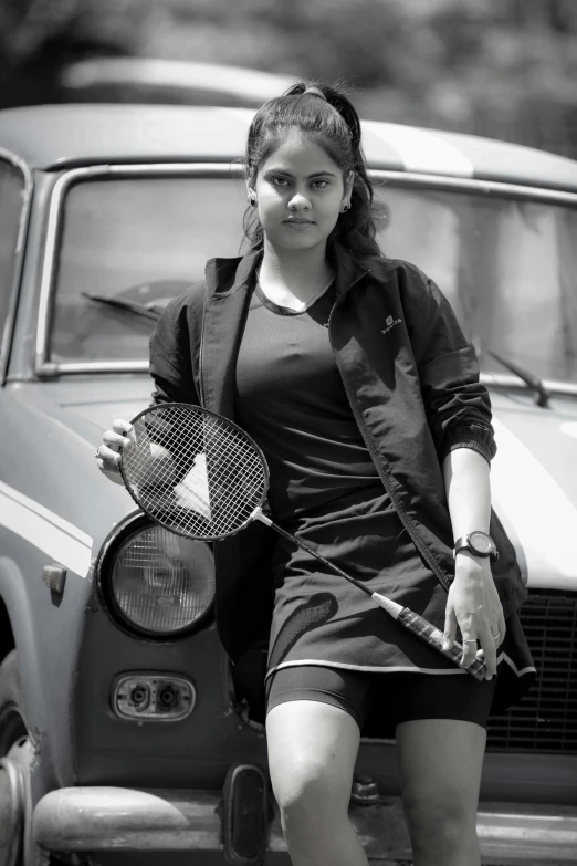 a woman sitting on top of a car holding a tennis racket, inspired by T. K. Padmini, pexels contest winner, girl wearing uniform, black and grey, portait photo profile picture, sport