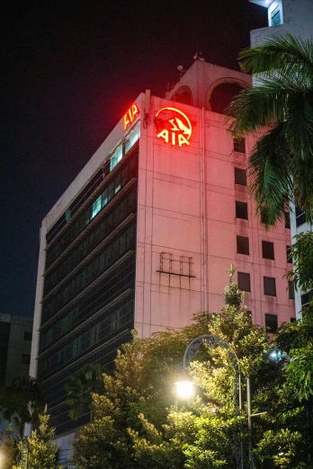 a tall building with a neon sign on top of it, by Dr. Atl, air technology, manila, atari logo, atmospheric red lighting