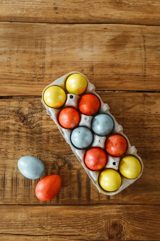 a carton of eggs sitting on top of a wooden table, rainbow sheen, payne's grey and venetian red, pastelle colors, bombs