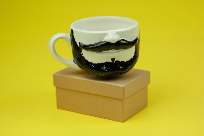 a close up of a coffee cup with a mustache on it, inspired by Muggur, pop art, inside its box, monochrome 3 d model, handmade pottery, with a full black beard