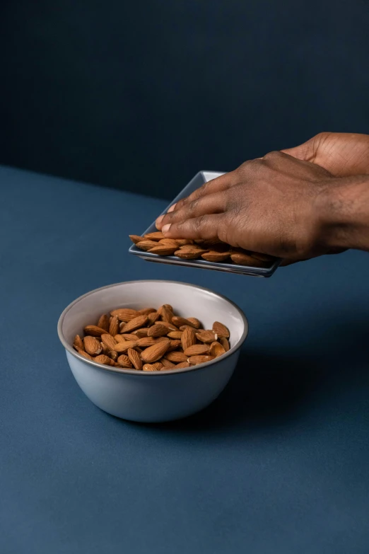 a person reaching for a bowl of almonds, inspired by Peter de Sève, angled, sleek, award - winning crisp details, quick assembly