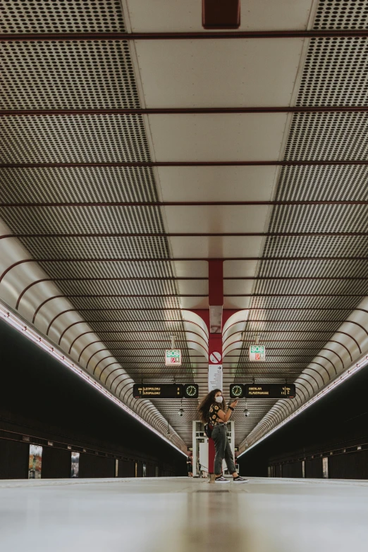 a couple of people that are standing in a train station, inspired by Andreas Gursky, unsplash, postminimalism, intricate detailed roof, red brown and white color scheme, lights on ceiling, 2 5 6 x 2 5 6