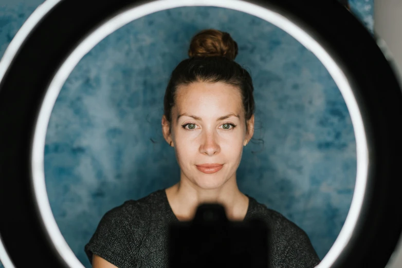 a woman taking a picture of herself in a mirror, a portrait, by Emma Andijewska, unsplash contest winner, hurufiyya, ring light, with a blue background, 4k symmetrical portrait, in front of a black background