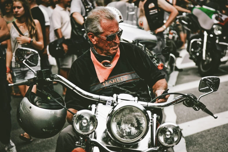 a man riding on the back of a motorcycle down a street, pexels contest winner, photorealism, the look of an elderly person, in style of chrome hearts, in front of a large crowd, profile image