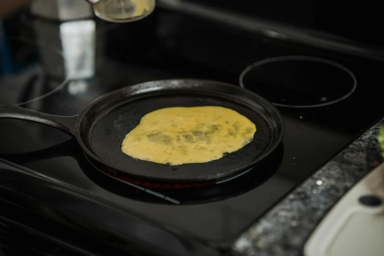 a close up of a frying pan on a stove, by Jessie Algie, unsplash, process art, manta ray made of pancake, yellow, slate, filling with water