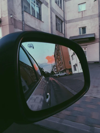 a rear view mirror of a car on a city street, a picture, inspired by Elsa Bleda, unsplash contest winner, trip to legnica, low quality photo, sunset photo, portait photo