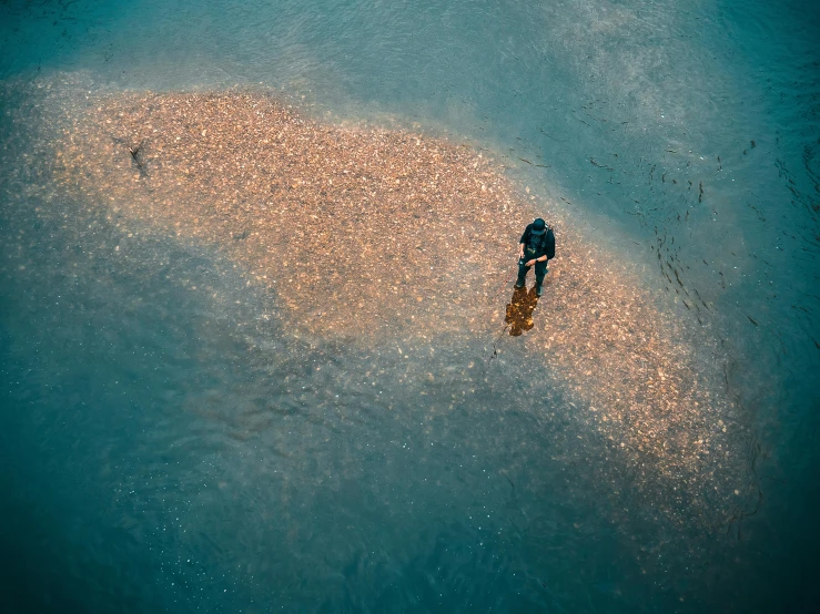 a person standing in the middle of a body of water, by Attila Meszlenyi, pexels contest winner, covered in coral and barnacles, aerial, people angling at the edge, gold