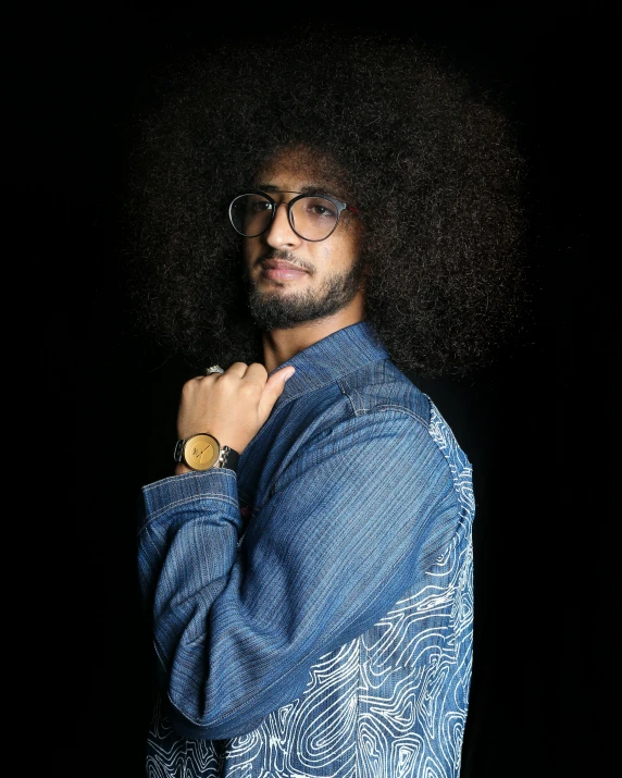 a man with an afro wearing glasses and a blue shirt, an album cover, by Lily Delissa Joseph, trending on pexels, les nabis, raden saleh, standing with a black background, big hair, ahmad merheb