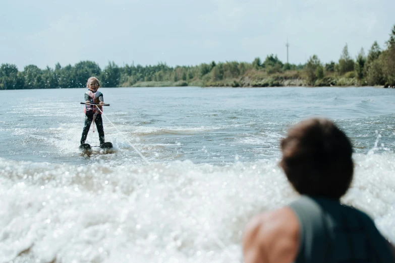 a man riding a wake board on top of a body of water, by Jacob Toorenvliet, pexels contest winner, hurufiyya, she is walking on a river, family friendly, anastasia ovchinnikova, cardboard