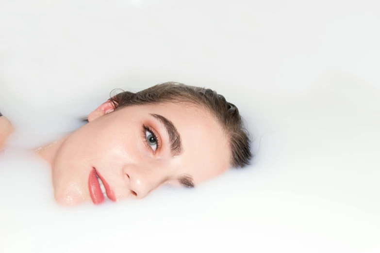 a woman taking a bubble bath in a bathtub, inspired by Elsa Bleda, trending on pexels, process art, large eyebrows, with a white background, portrait sophie mudd, half submerged
