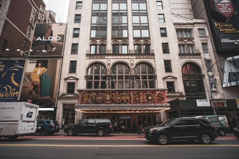 a group of cars driving down a street next to tall buildings, an album cover, by Niko Henrichon, unsplash, art nouveau, photo of a big theaterstage, new york buildings, portrait of gigachad, exterior view