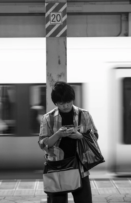 a black and white photo of a man looking at his phone, happening, platforms, asian human, square, maintenance