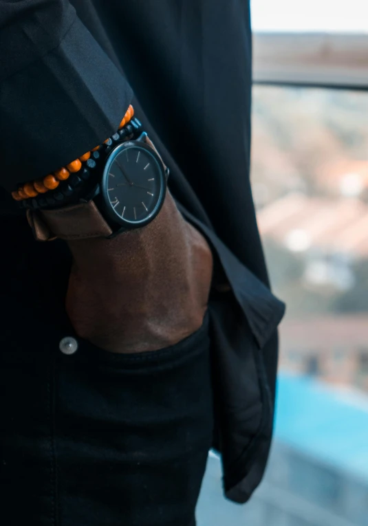 a close up of a person wearing a watch, inspired by Afewerk Tekle, pexels contest winner, black and orange coat, ( ( dark skin ) ), casual black clothing, regular build