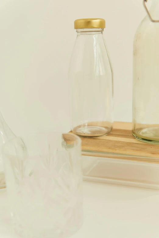 a couple of glass bottles sitting on top of a table, by Emma Geary, unsplash, visual art, light wood, super detail of each object, on clear background, sustainable