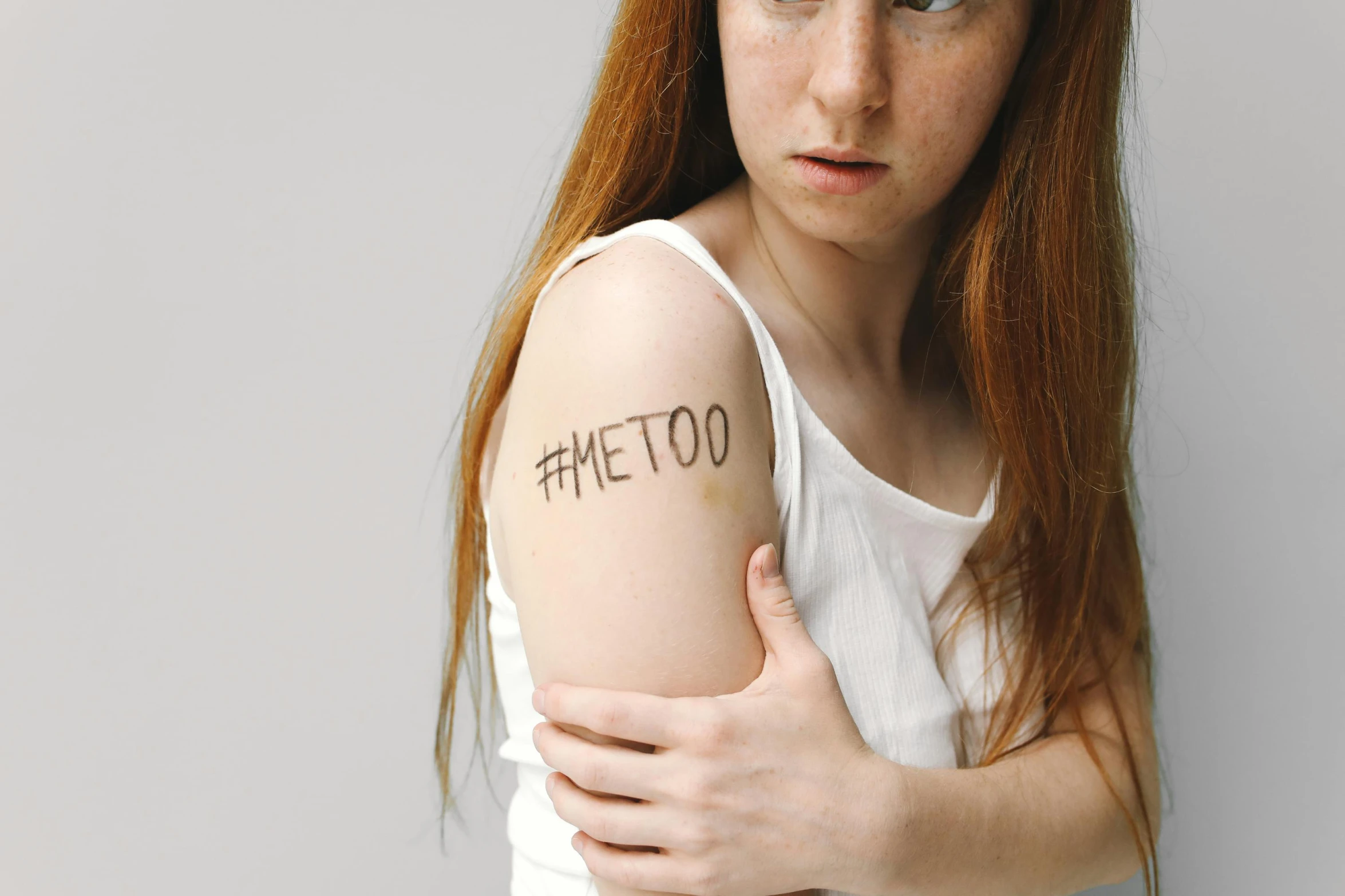 a woman with a tattoo on her arm, a tattoo, shutterstock, antipodeans, subject action: holding sign, ellie bamber, help me, white ribbon