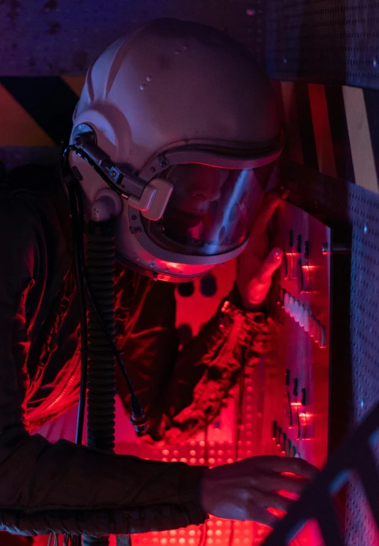 a man in a helmet and goggles working on a computer, by Greg Rutkowski, light and space, red skies, wearing human air force jumpsuit, close-up from above, profile image