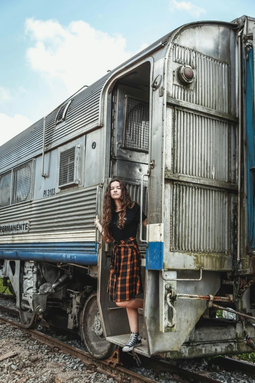 a woman standing in the doorway of a train, a portrait, pexels contest winner, renaissance, plaid skirt, portrait rugged girl, brunette, emily rajtkowski