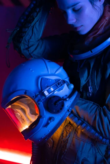 a woman in a space suit holding a helmet, pexels contest winner, light and space, blue and red lighting, airforce gear, detail shot, like a catalog photograph