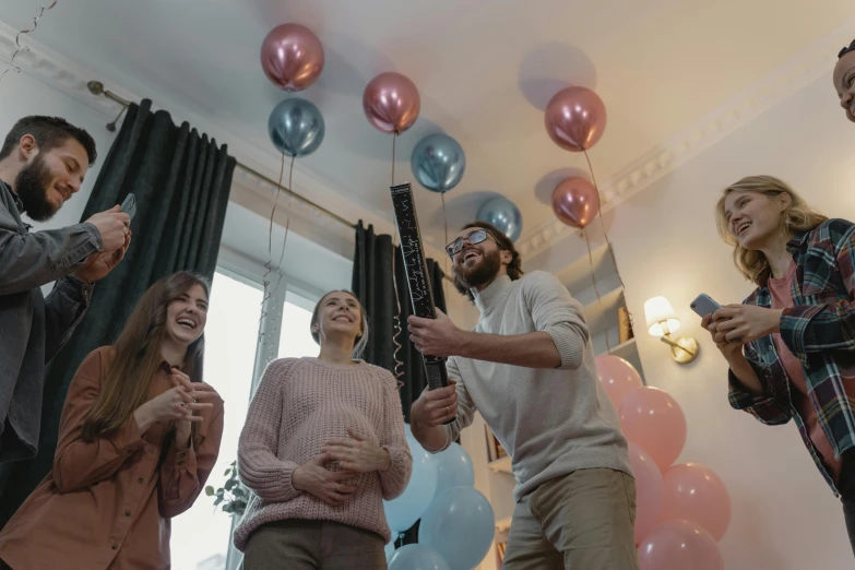 a group of people standing in a room with balloons, in a living room, profile image, pregnant, decorations