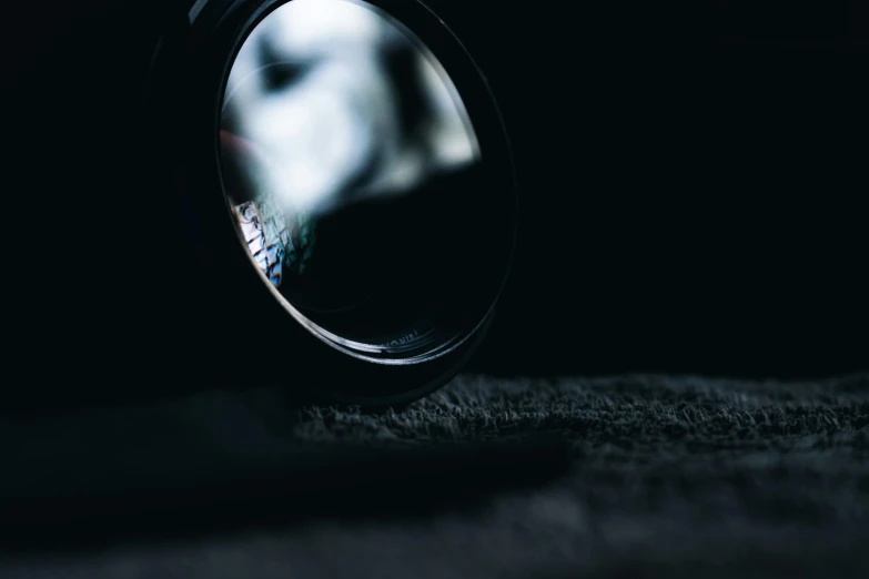 a close up of a camera lens on a table, unsplash, vantablack chiaroscuro, looking into a mirror, high res photograph, dimly - lit