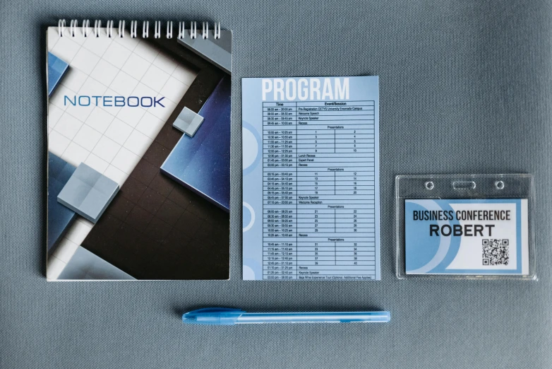 a notebook sitting on top of a table next to a pen, full color catalog print, grey and blue theme, whiteboards, reboot