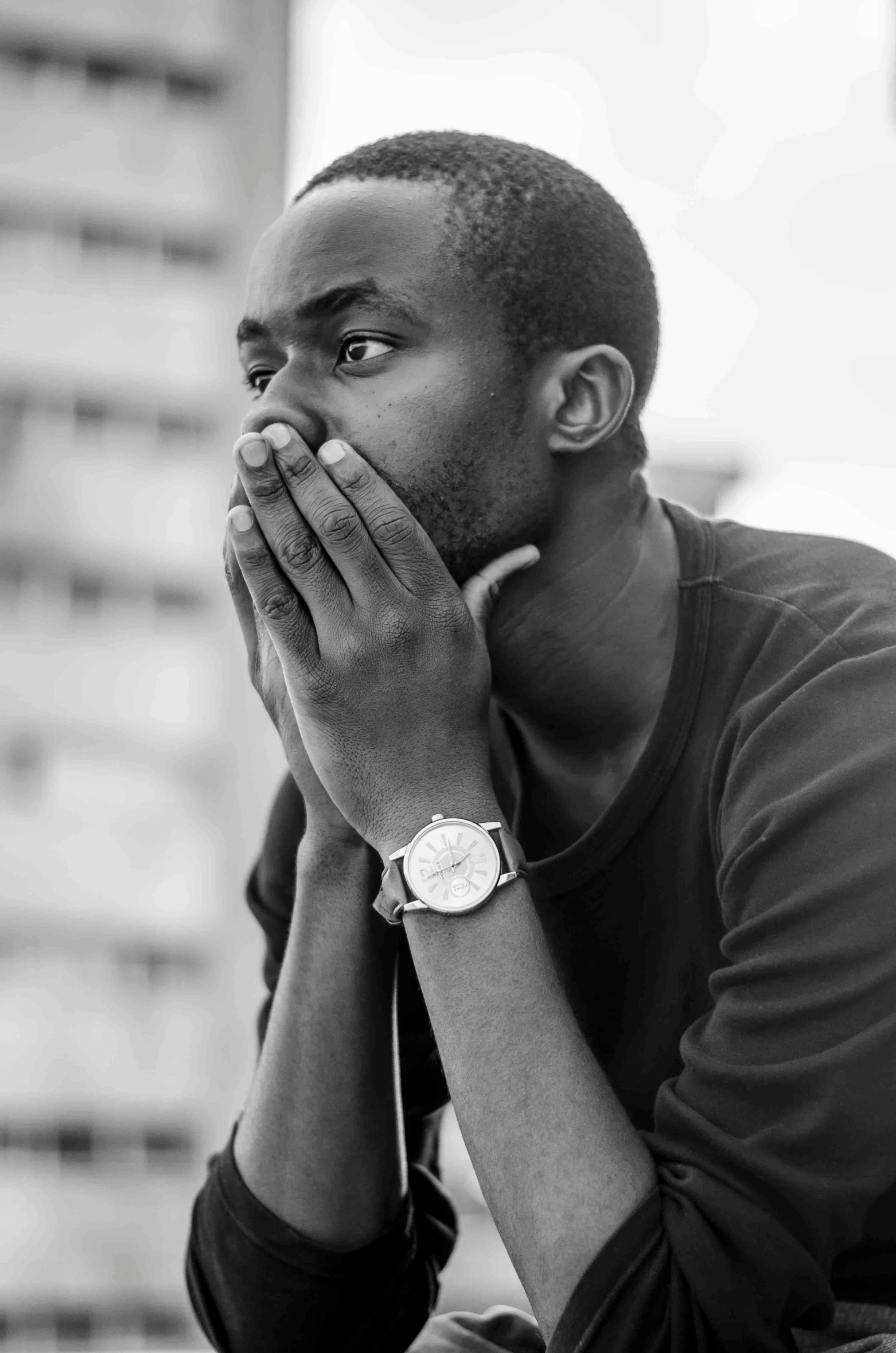 a black and white photo of a man with his hands on his face, a black and white photo, by Afewerk Tekle, looking distracted and awkward, unmistakably kenyan, yzy gap, chilled out smirk on face