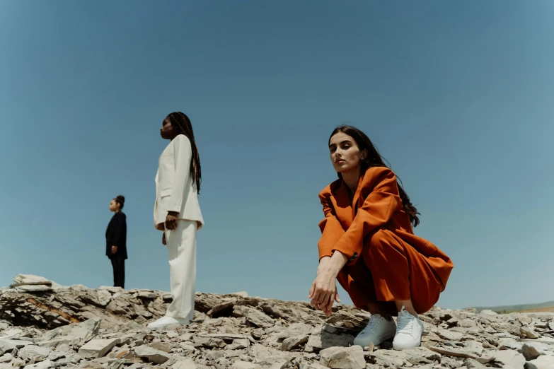 a woman kneeling on top of a pile of rocks, an album cover, pexels contest winner, antipodeans, wearing white suit, charli bowater and artgeem, wearing a track suit, asher duran