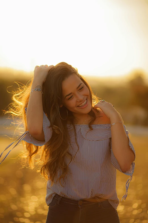 a woman standing in a field with her hair blowing in the wind, perfect smile, sun setting, jewelry, uploaded