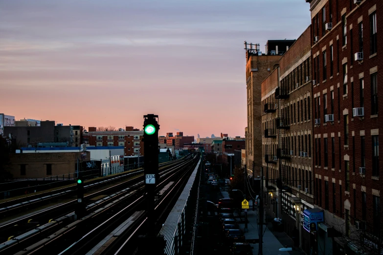 a green traffic light sitting on the side of a train track, by Washington Allston, unsplash, renaissance, vista of a city at sunset, chicago, ignant, bustling city