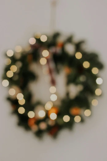 a close up of a christmas wreath on a wall, by Carey Morris, pexels, muted lights, on a pale background, multiple stories, blurry image
