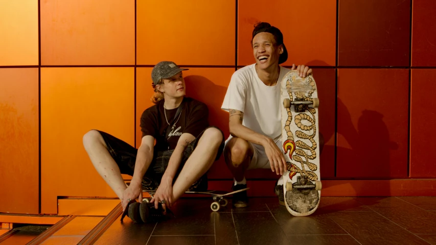 a couple of people sitting next to each other with a skateboard, lee griggs and jason chan, orange tint, lachlan bailey, profile image