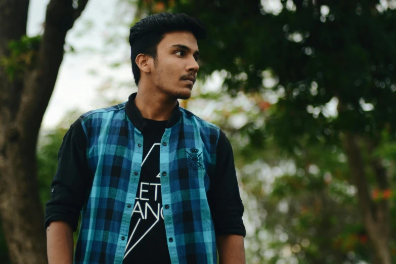 a young man standing in front of a tree, inspired by Thota Vaikuntham, unsplash, hurufiyya, wearing a plaid shirt, avatar image, streetwear, blue and black