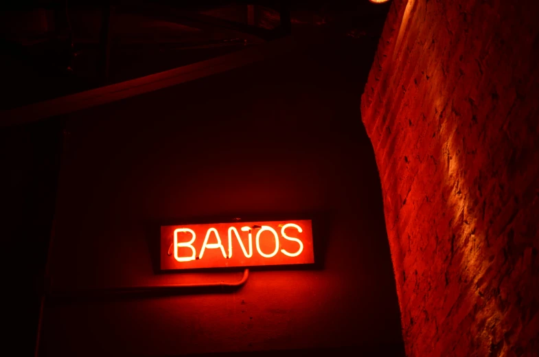 a red neon sign hanging from the side of a building, an album cover, by Dennis Flanders, trending on unsplash, bauhaus, wooden banks, spanish, saturday night in a saloon, fanoos